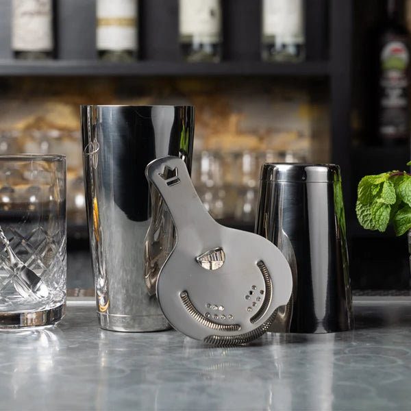 1121 Cocktail Kingdom Koriko Set of 2 Weighted Tins in stainless steel with strainer and mixing glass on marble bar top.
