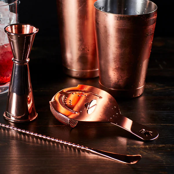 1126 C Cocktail Kingdom Koriko Hawthorne Strainer show with copper shaker, mixing spoon, and jigger on copper table top.