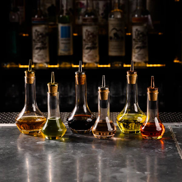 Cocktail Kingdom Beveled Bitters Bottle with Cork Dasher Top 1.7oz shown in bar setting with various bitters. 