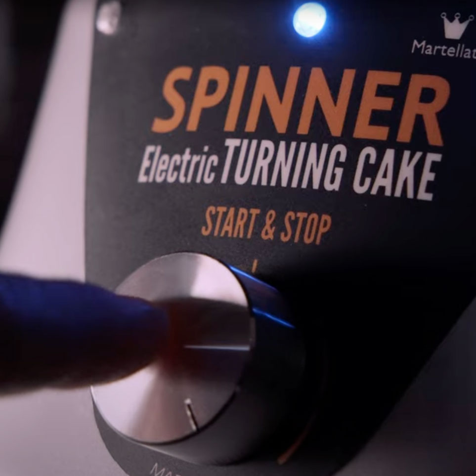 Close up picture of the dial and lights on the front of the silver and black electric cake spinner. 