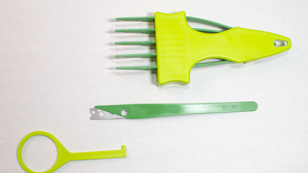 Light and dark green 6 blade bread lame or bread scorer with one blade removed next to the lame and the tool to remove the blades beside it. 