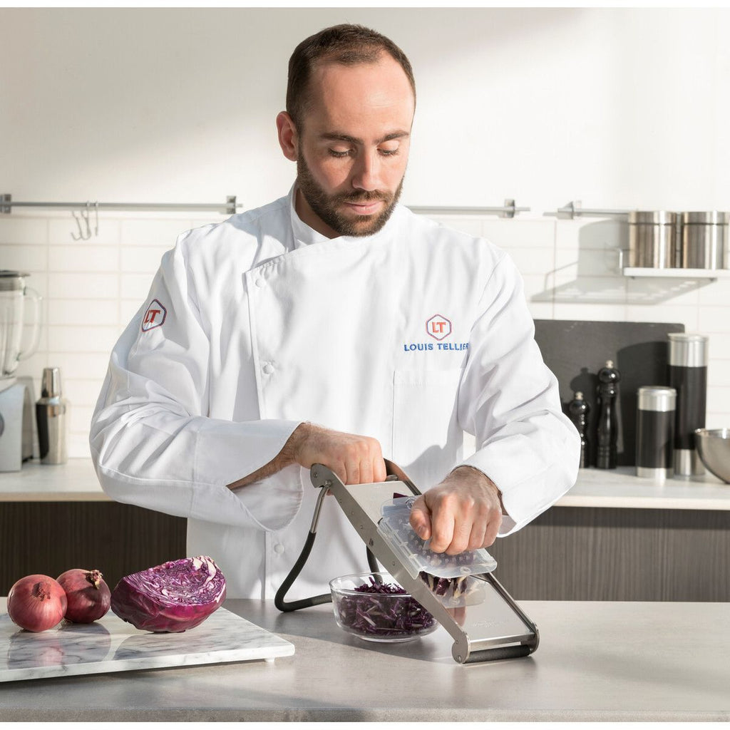 Chef in a professional kitchen using a mandoline slicer.