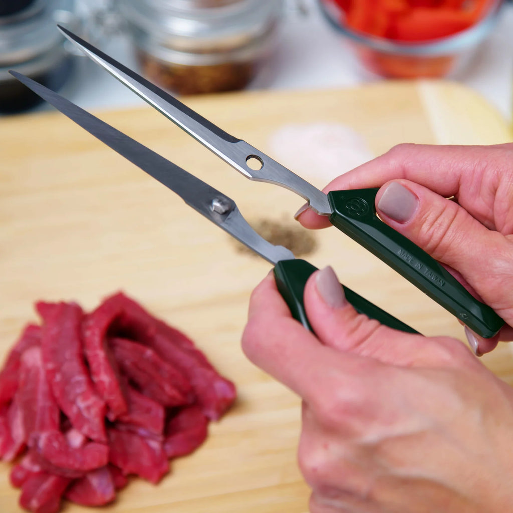 Joyce Chen Scissors in dark olive shot separated over wood cutting board with meat.