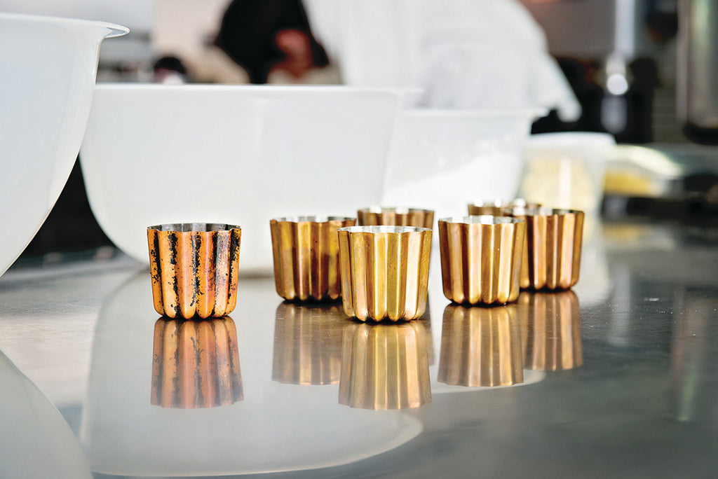 Copper colored tin molds on a reflective surface with blurred background