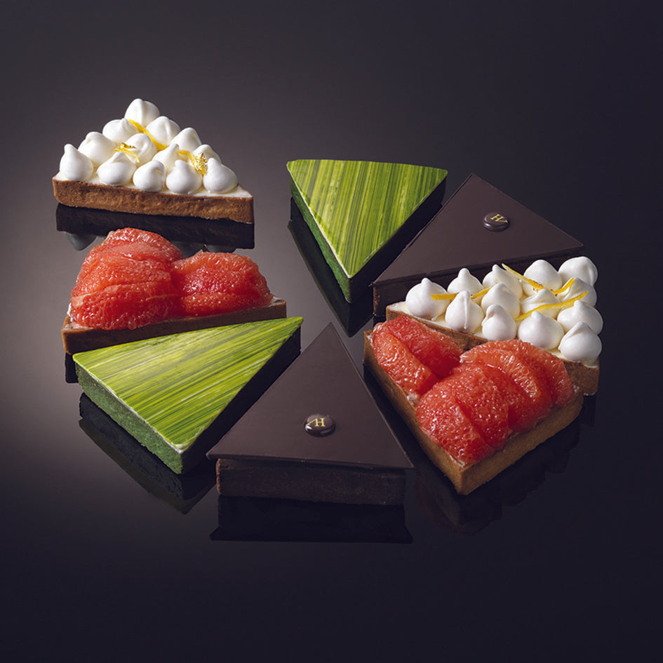 Three triangular desserts with different toppings on a black background