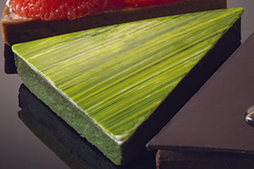 Green triangular pastry on a reflective surface.