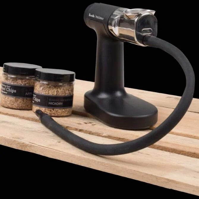 Smoking Gun Pro with wood chop accessories on wood table, black background.  
