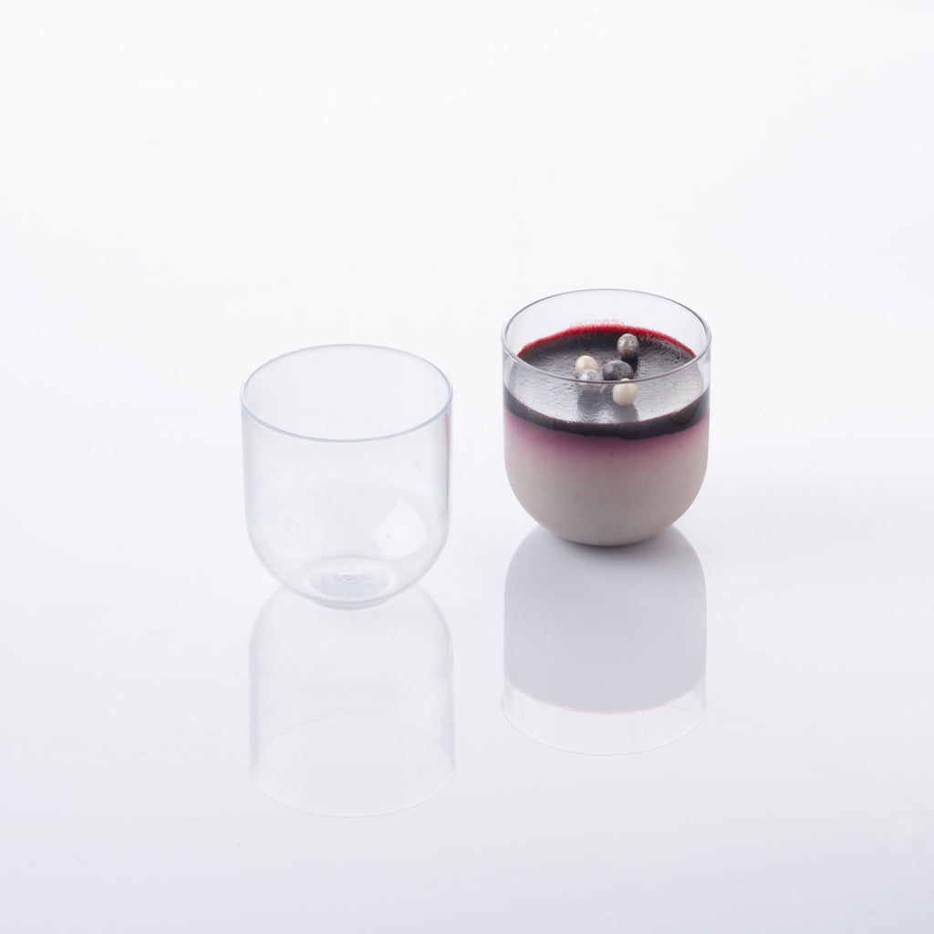 2 Plastic Tumblers , one empty, one full with white and purple pastry and garnished. Shot on white silo background.