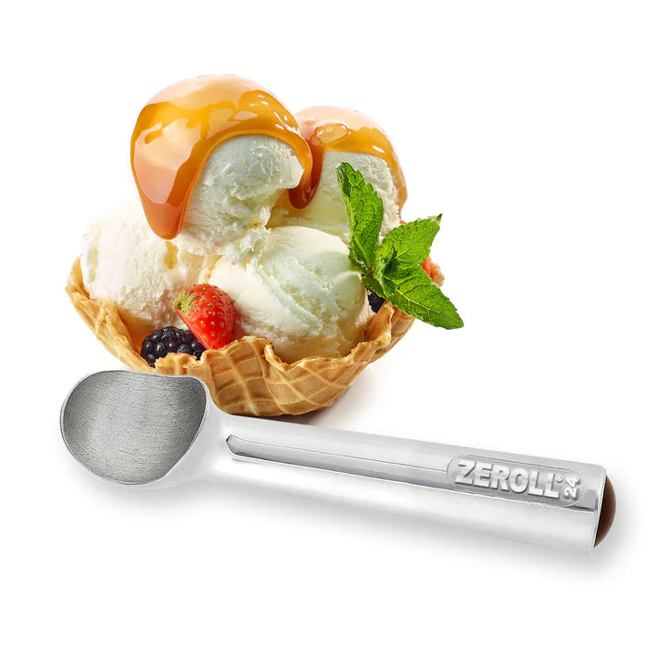Ice cream in a waffle bowl with caramel sauce, berries, and a Zeroll ice cream scoop on a white background