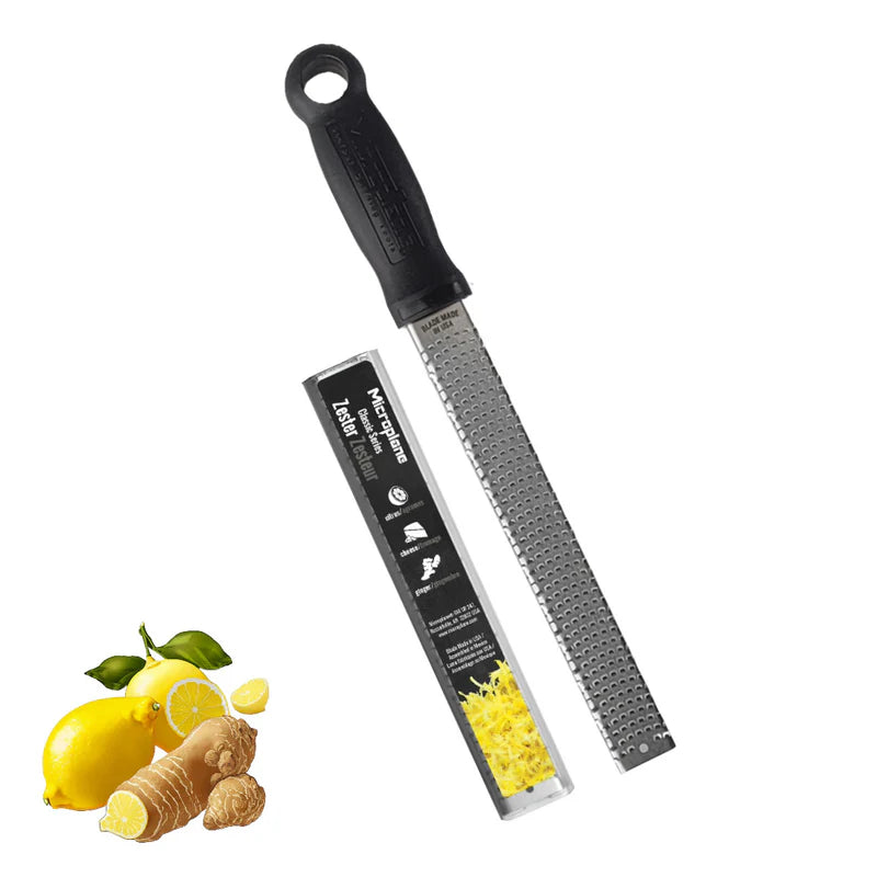U746 Microplane zester with a black handle and silver blade, accompanied by lemons and ginger on a white background.