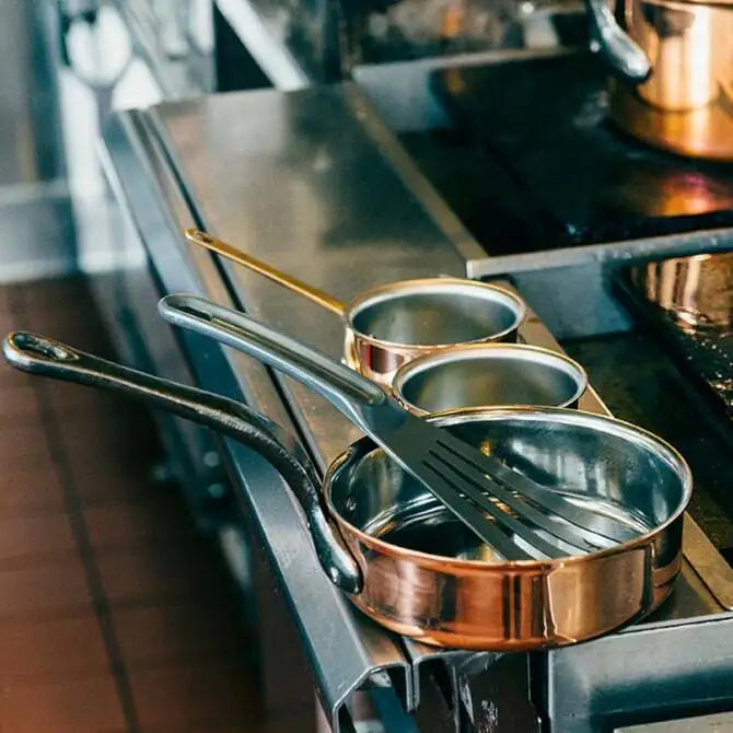 U833 Slotted Spatula shown in professional kitchen setting laying in a copper pot.