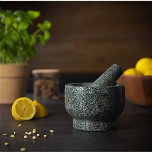 UA276 Mortar and Pestle on dark table with spices and lemon in background.