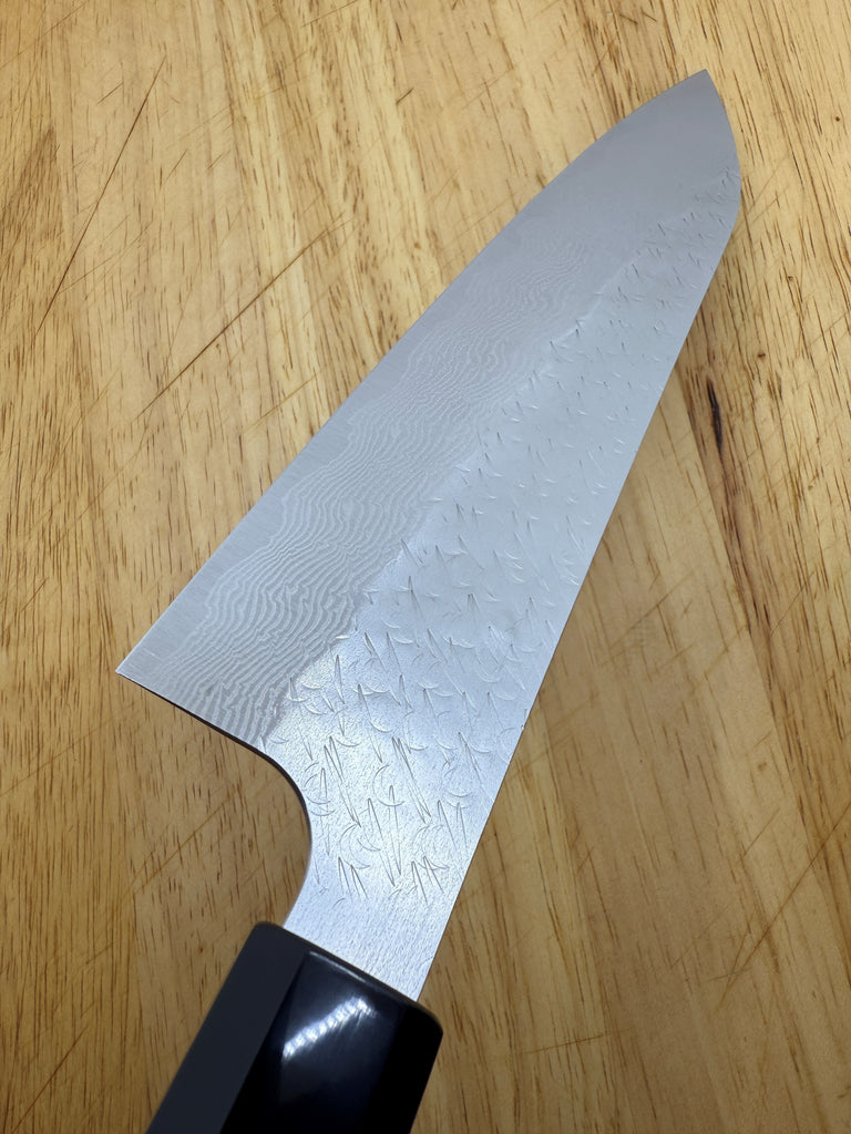 Z550 Nigara SG Strix Gyuto 210mm with black ebony handle showing blade detail on brown wooden cutting board.